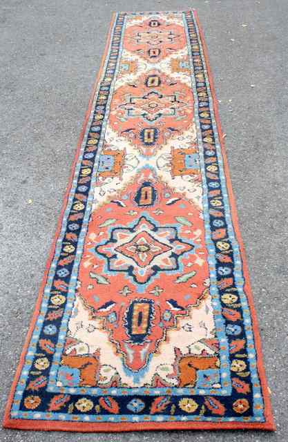 Appraisal: AN INDIAN RUST GROUND RUNNER decorated interlocking medallions within a