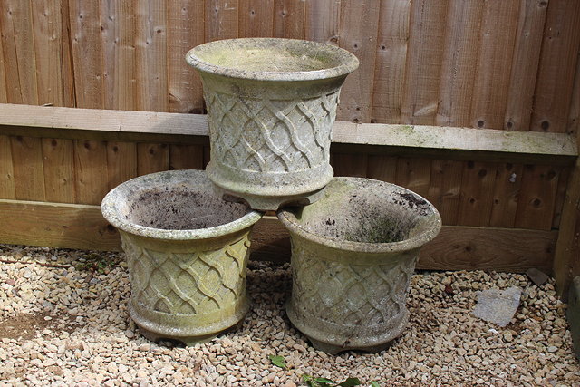 Appraisal: A SET OF THREE RECONSTITUTED STONE PLANTERS with flaring rims