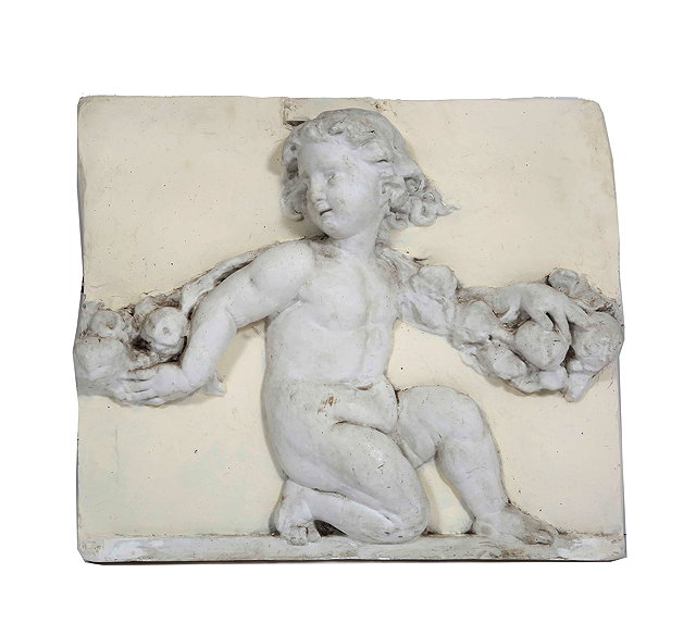 Appraisal: AN OLD PLASTER PLAQUE depicting a cherub supporting a bough