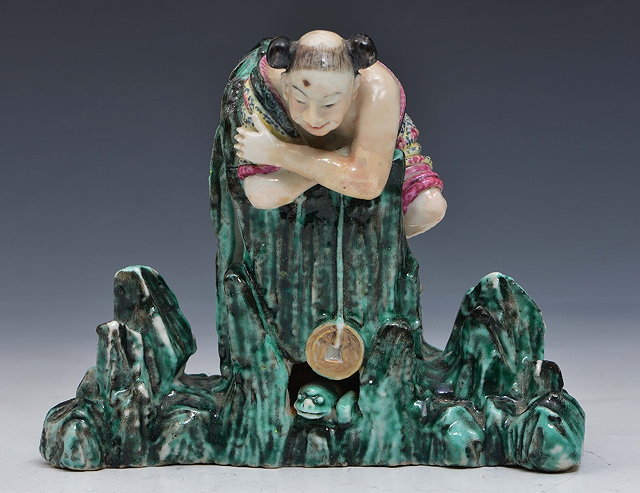 Appraisal: A CHINESE CANTON MODEL OF A FIGURE leaning over rockwork