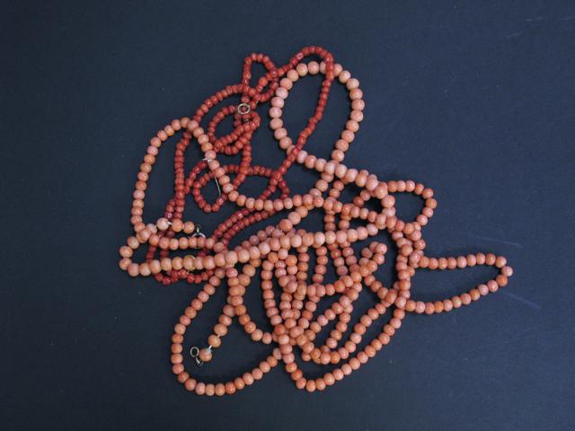 Appraisal: TWO STRINGS OF CORAL BEADS and a three strand coral