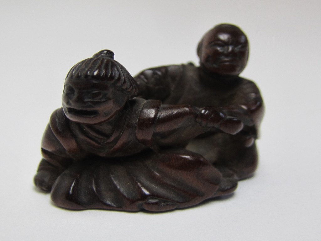 Appraisal: A Japanese carved wood netsuke of two figures one restraining