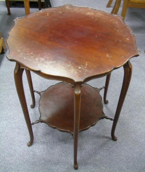 Appraisal: An Edwardian mahogany table with triple end standards and platform