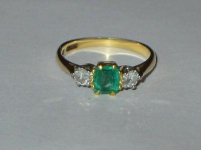 Appraisal: AN EMERALD AND DIAMOND RING the trapp cut central emerald