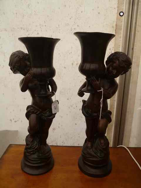 Appraisal: A PAIR OF BRONZE SCULPTURES of Putti supporting campana urns