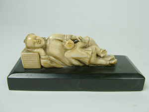 Appraisal: A Chinese carved ivory figure group of a reclining figure