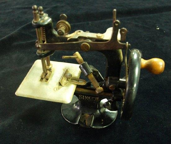 Appraisal: A miniature Singer sewing machine the wheel with turned wooden