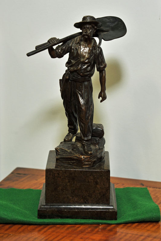 Appraisal: BRONZE SCULPTURE Depicting a miner with tools over his shoulder