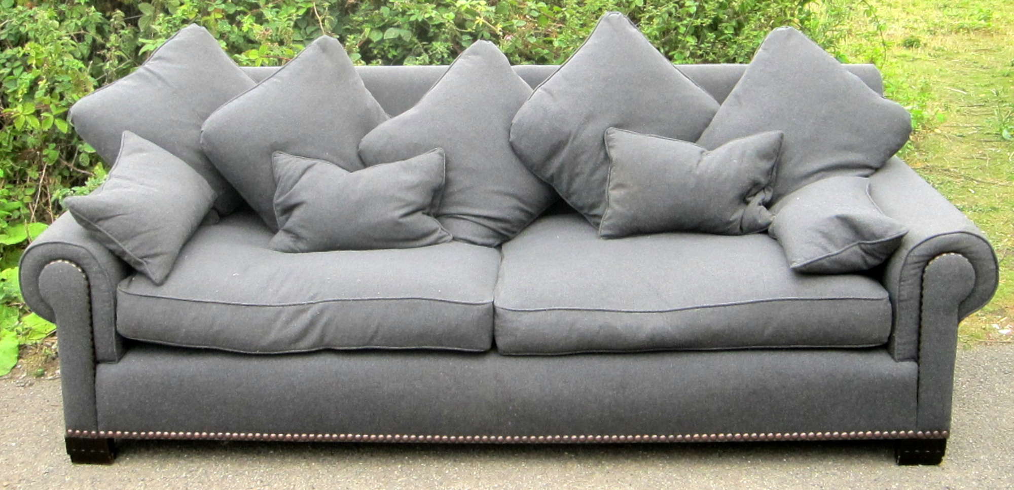 Appraisal: Large dark grey upholstered settee with cushions on black wooden