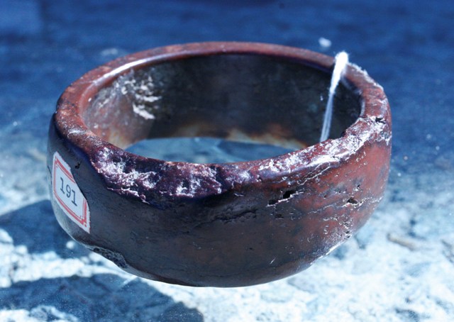 Appraisal: A bangle in an iron red stone possibly neolithic damage