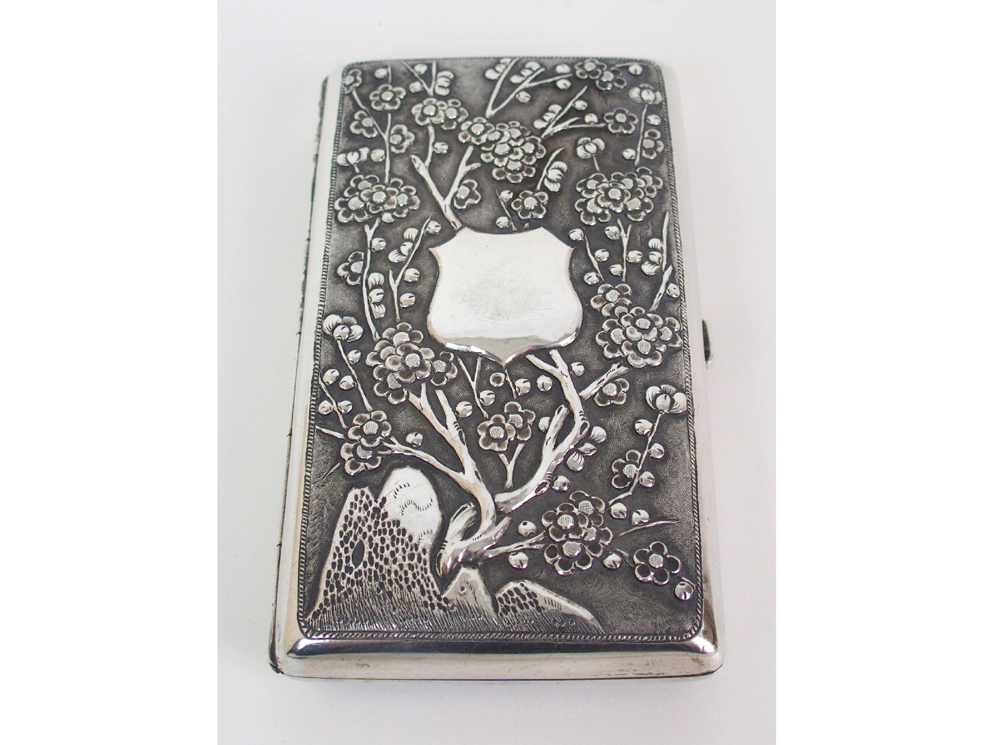 Appraisal: A Japanese silver cigarette caseembossed with blossoming branches issuing from