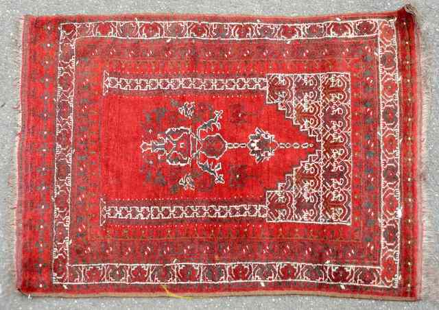 Appraisal: AN AFGHAN WINE GROUND RUG decorated with a central arch