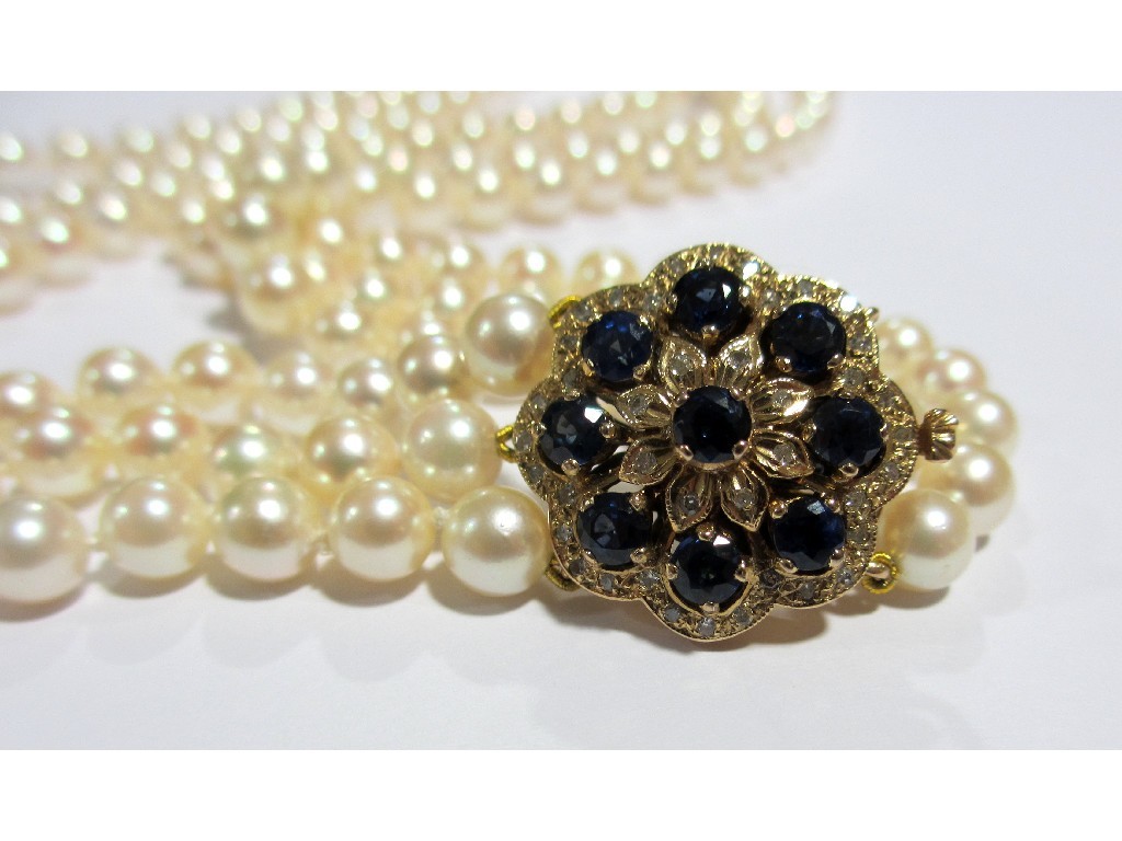 Appraisal: A triple strand pearl necklace with sapphire and diamond clasp