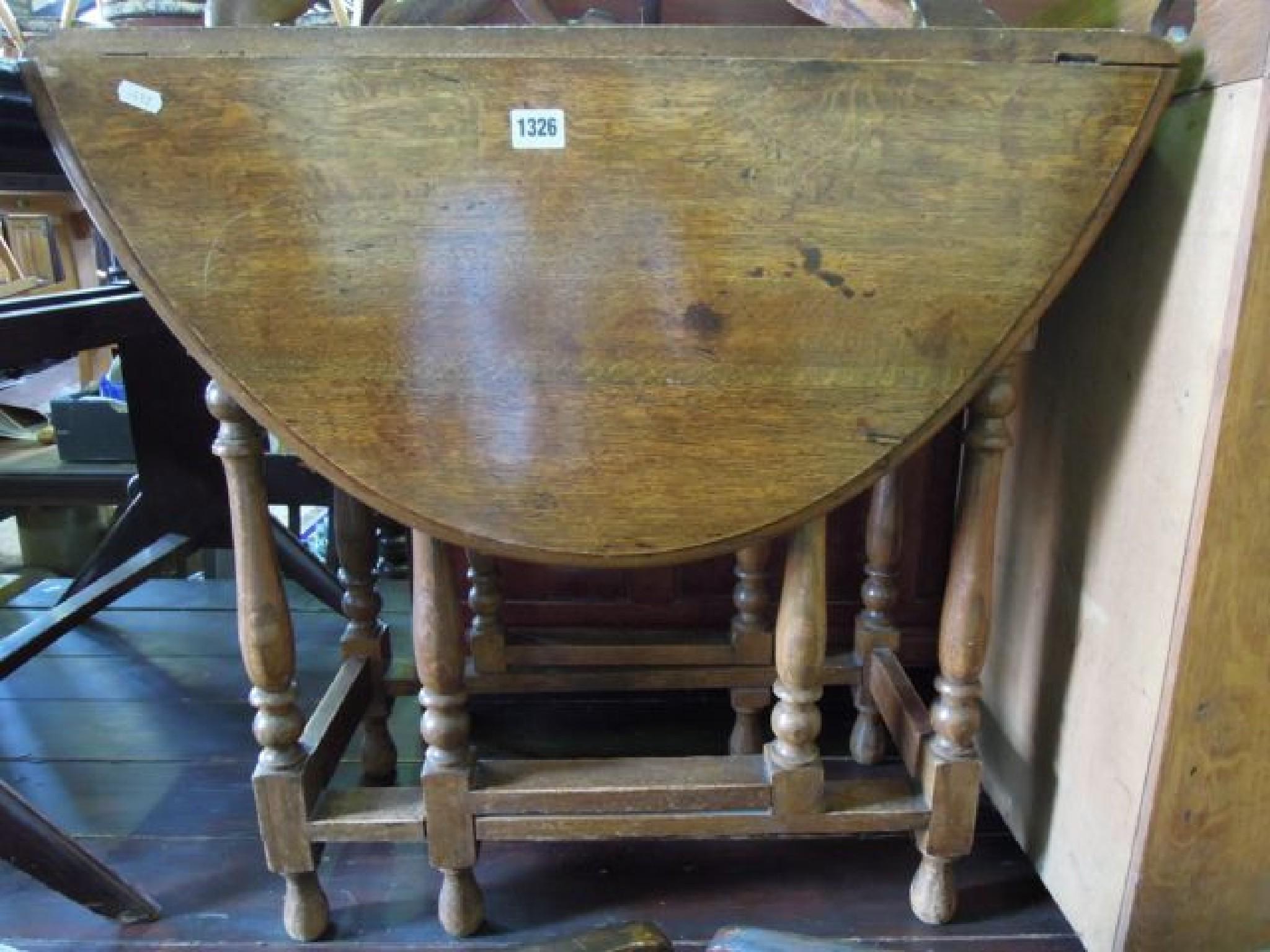 Appraisal: An oak oval drop leaf table raised on turned column