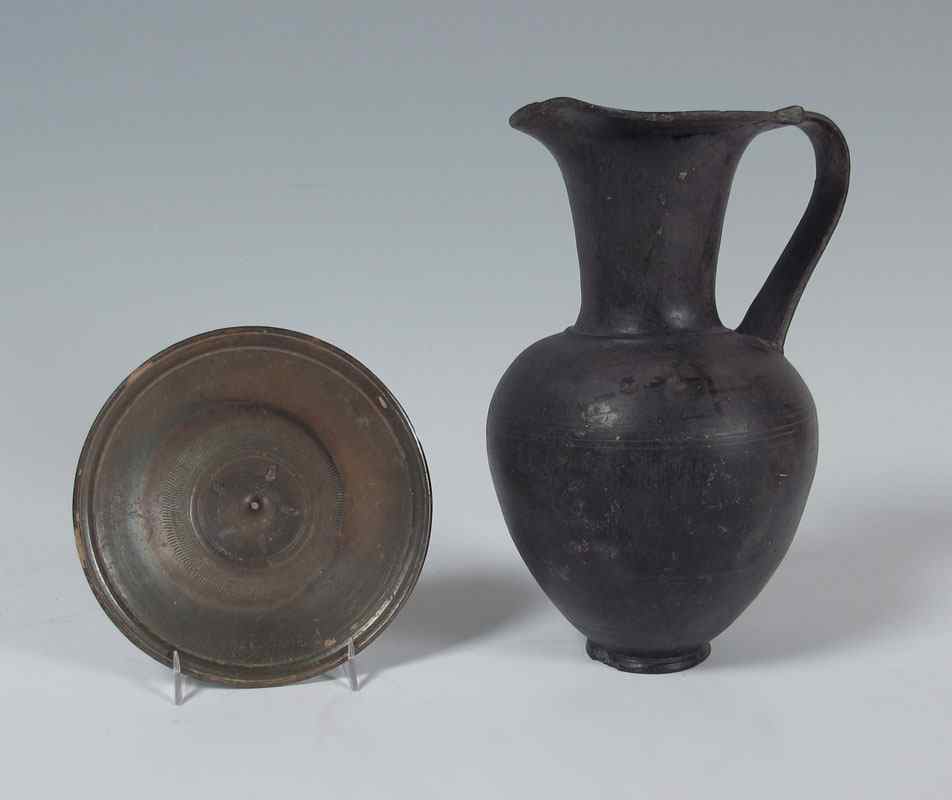 Appraisal: GREEK BLACK OINOCHOE BUCCHERO SAUCER To include Black pottery oinochoe