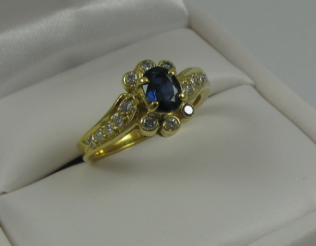 Appraisal: SAPPHIRE DIAMOND AND K GOLD RING centering an oval-cut blue