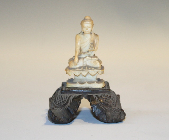 Appraisal: AN INDIAN CARVED IVORY MINIATURE SEATED DEITY on a wooden