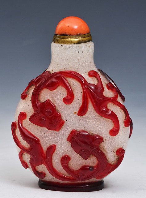 Appraisal: A BEIJING GLASS SNUFF BOTTLE carved in relief with four