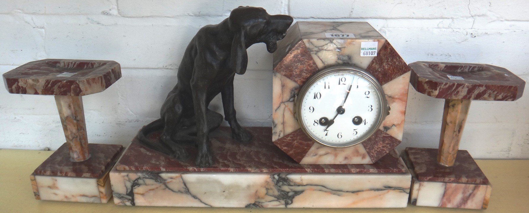 Appraisal: A French Art Deco clock garniture the multicoloured marble clock