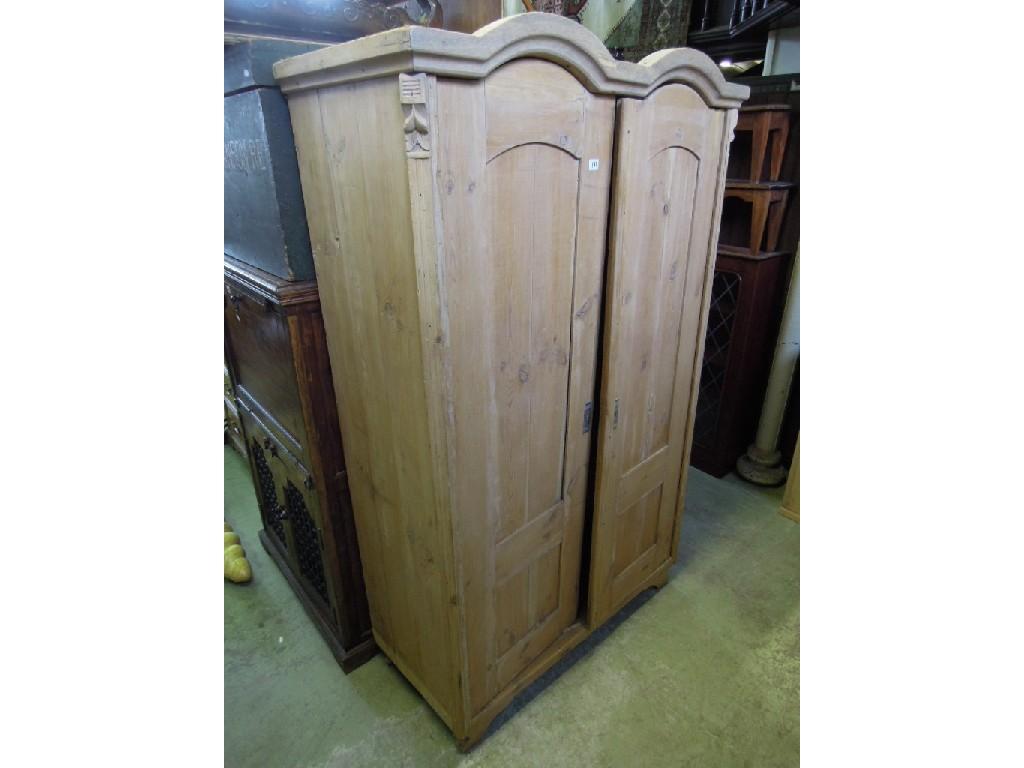 Appraisal: A continental stripped pine wardrobe with double arched top enclosing