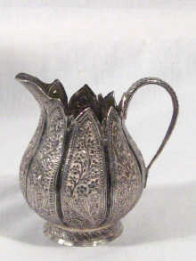 Appraisal: An Indian silver cream jug of lotus design with embossed