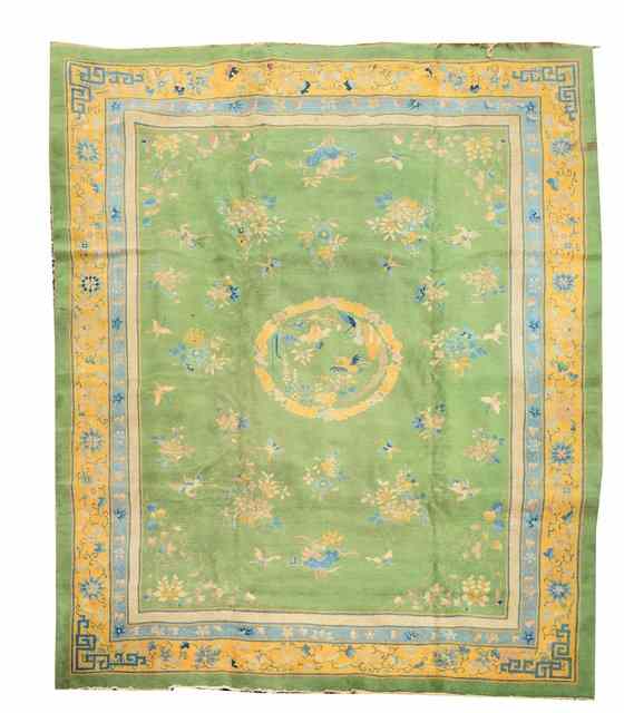 Appraisal: A CHINESE APPLE GREEN GROUND CARPET decorated storks and butterflies