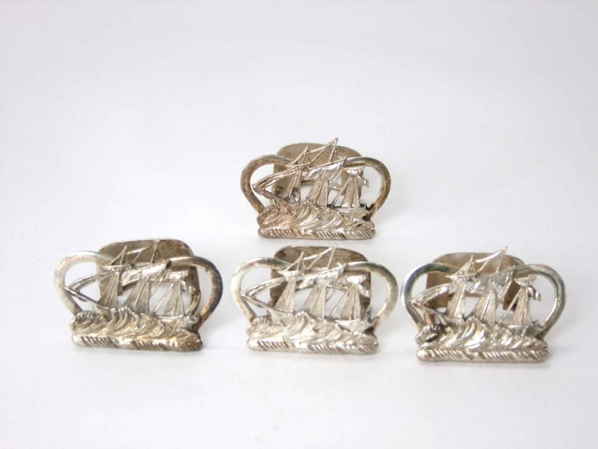 Appraisal: A set of four silver menu card holders each depicting