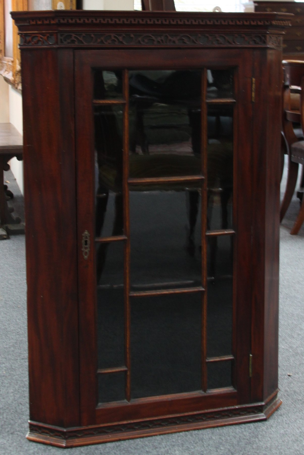 Appraisal: A mahogany corner cupboard with blind fret carved cornice enclosed