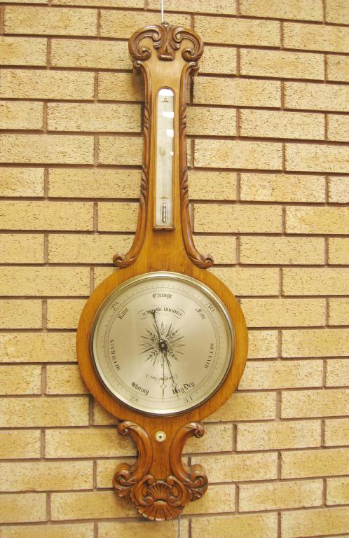 Appraisal: A large Victorian oak Mercury Wheel Barometer with carved scroll