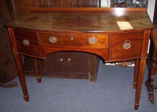 Appraisal: A mahogany bowfront kneehole sideboard fitted a surround of three