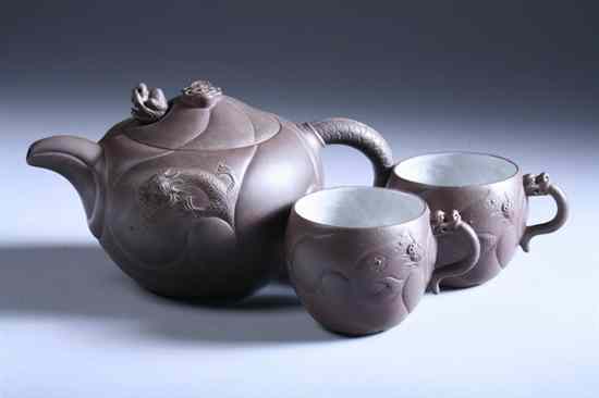 Appraisal: CHINESE YIXING TEAPOT AND TWO CUPS Dragon decoration with fitted