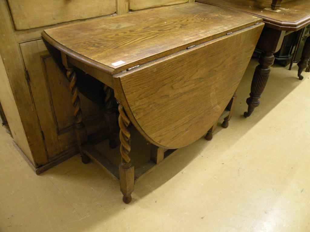 Appraisal: An oak oval drop leaf table on barley twist supports