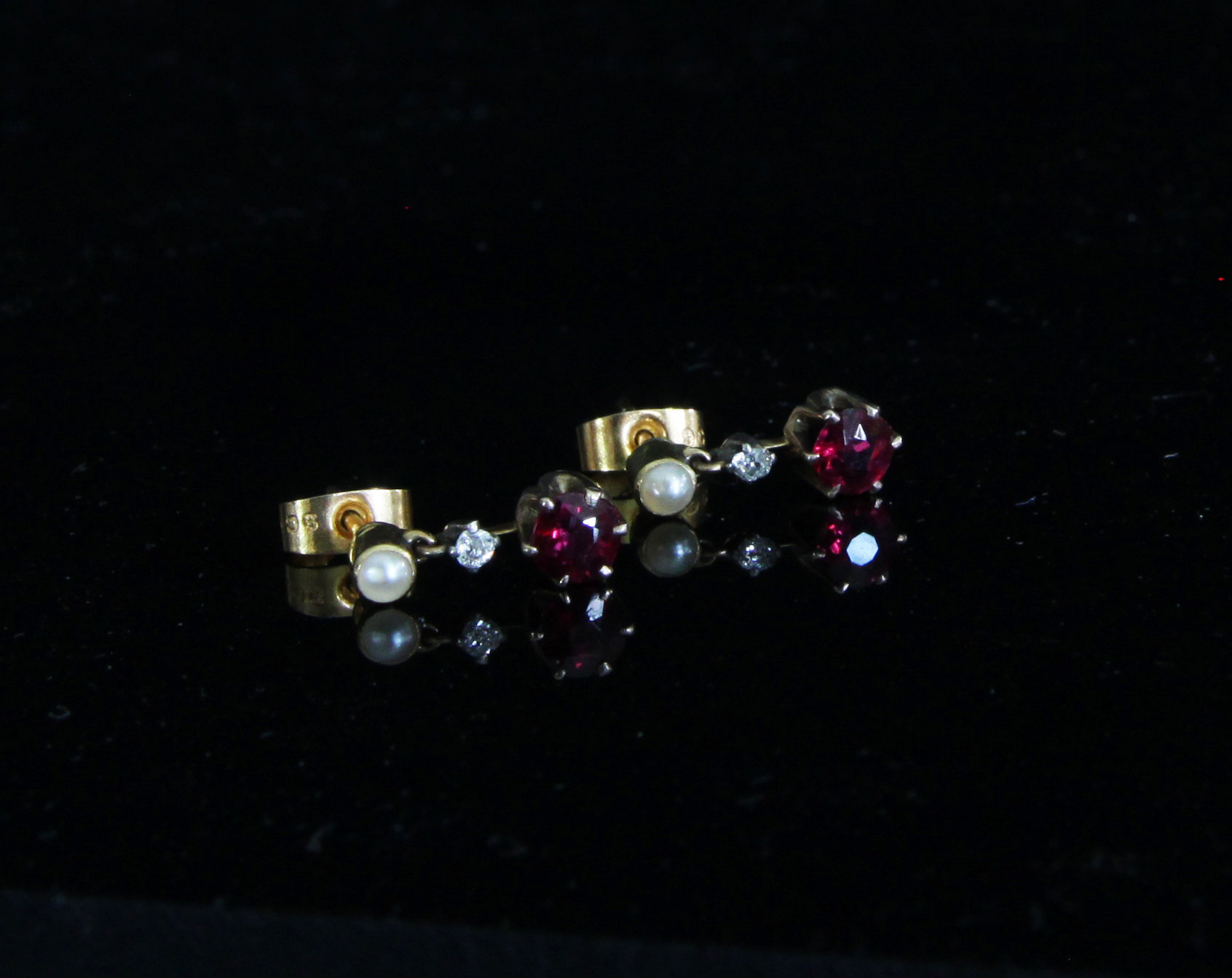 Appraisal: A pair of ruby drop earrings suspended below a pearl