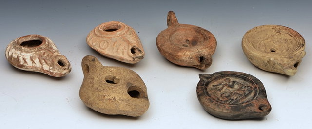 Appraisal: A GROUP OF SIX POTTERY OIL LAMPS of varying style