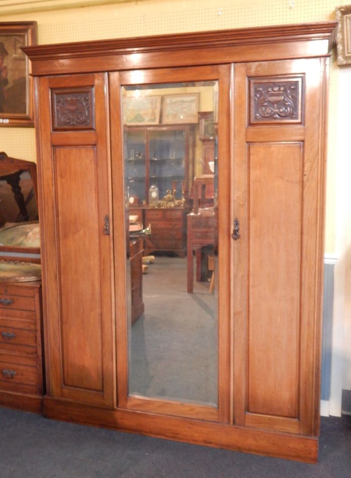 Appraisal: A late Victorian walnut triple wardrobe with central mirror plate