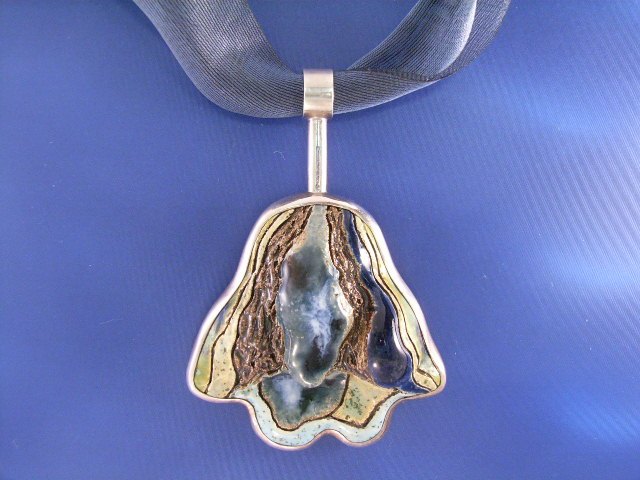 Appraisal: A hand painted ceramic pendant signed GD on a ribbon