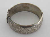 Appraisal: A hinged engraved oval silver bangle x cm internal Wt