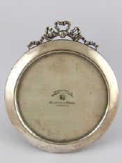 Appraisal: A circular photo frame with ribbon cresting and leather strut