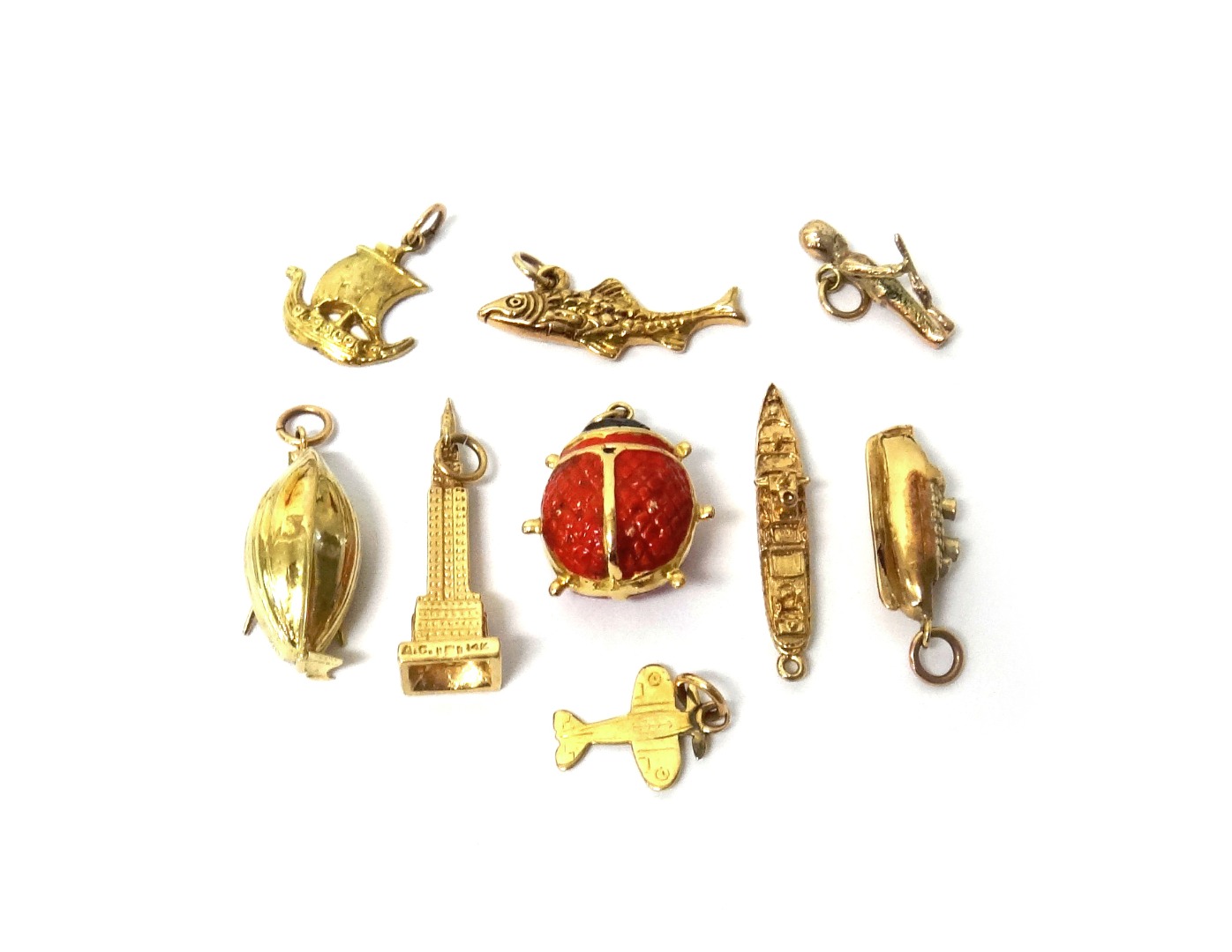 Appraisal: NIne gold charms comprising four ships and boats a fish