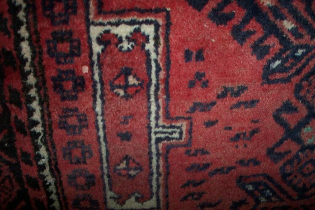 Appraisal: A red ground Eastern wool rug with hooked and geometric