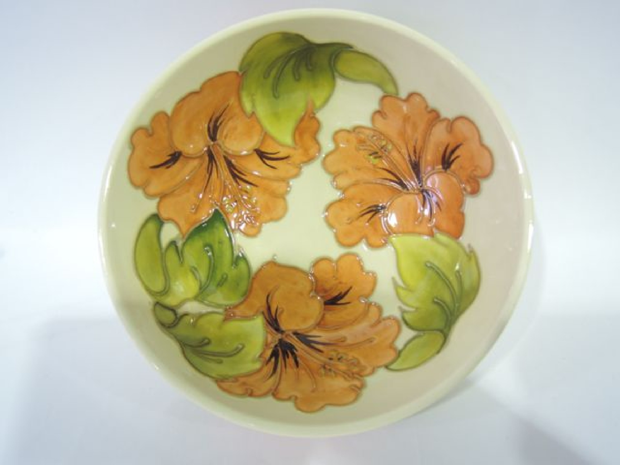 Appraisal: A cream ground Moorcroft bowl with orange and green hibiscus