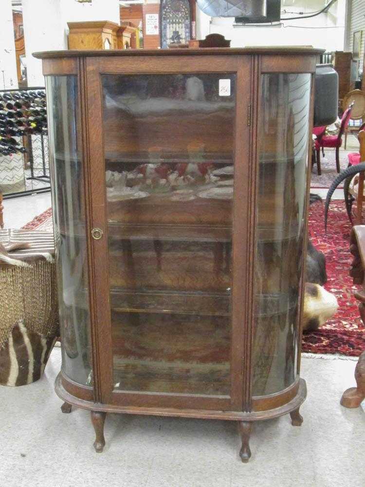 Appraisal: AN OAK AND CURVED GLASS CHINA CABINET American c with