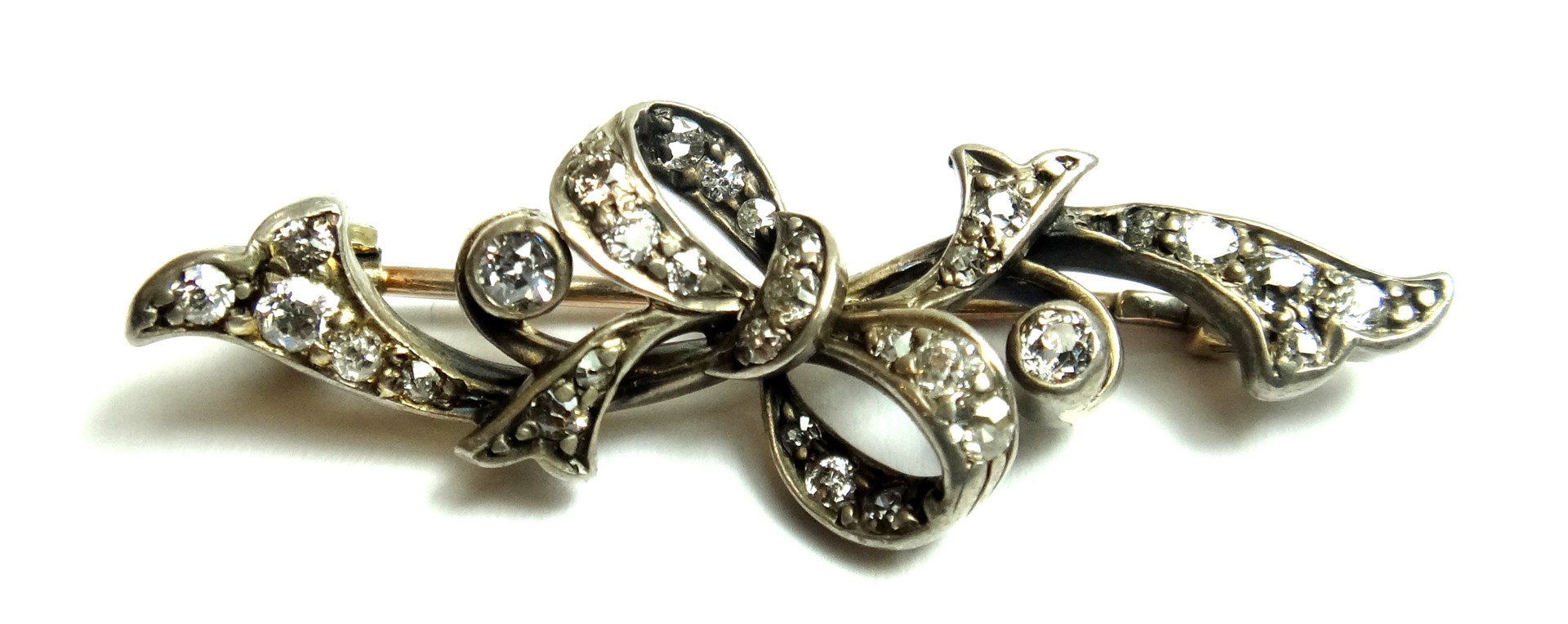 Appraisal: A diamond set brooch in a scrolling and bow shaped