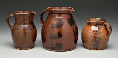 Appraisal: Three redware pitchers all with manganese splash decoration one with