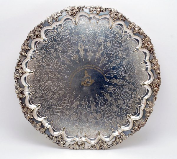 Appraisal: Large silverplate footed charger with grape scalloped border Engraved at