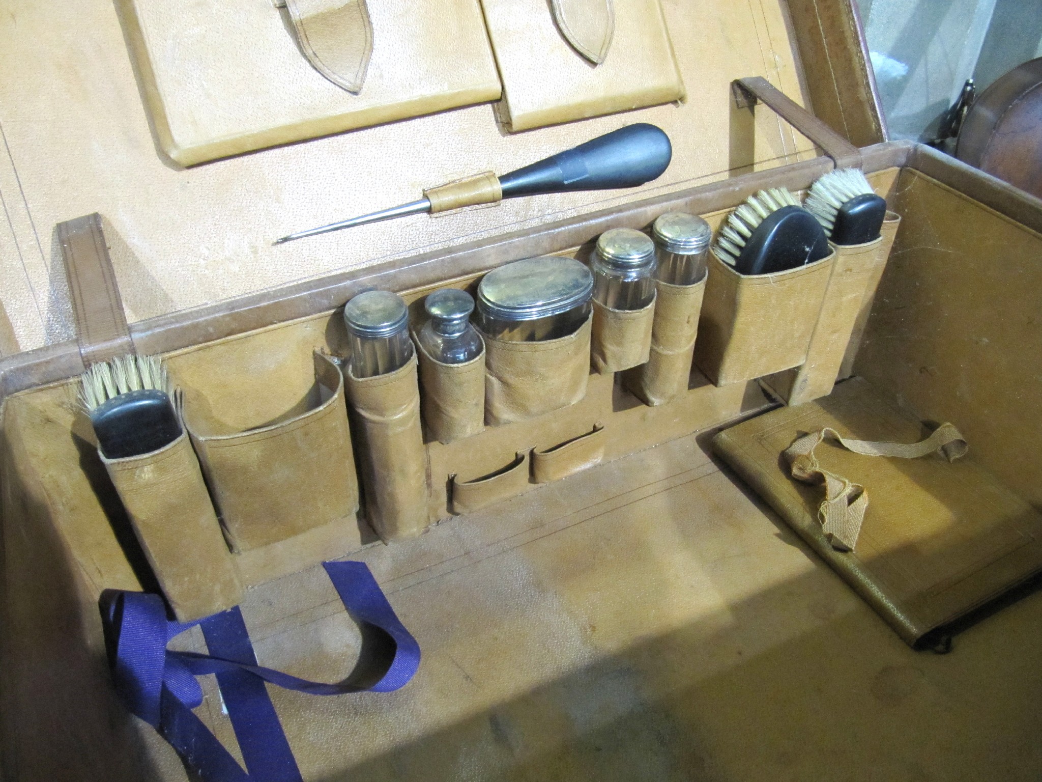 Appraisal: A leather travel case partially fitted with silver topped jars