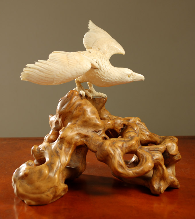 Appraisal: CARVED IVORY BIRD SCULPTURE mounted to a natural burl wood