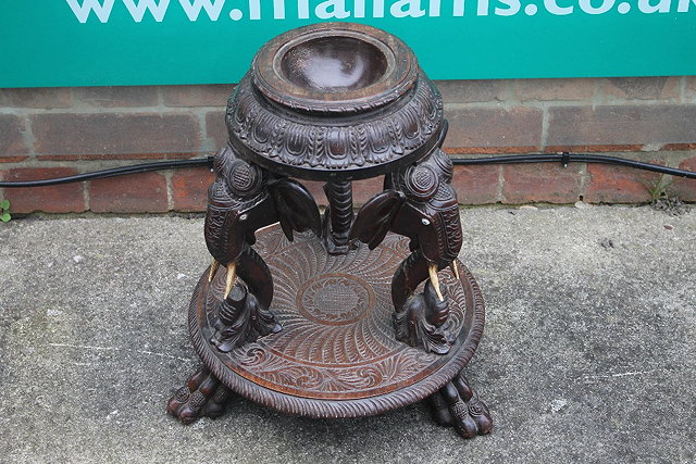 Appraisal: AN INDIAN HARDWOOD CARVED PLANT STAND with three carved elephant