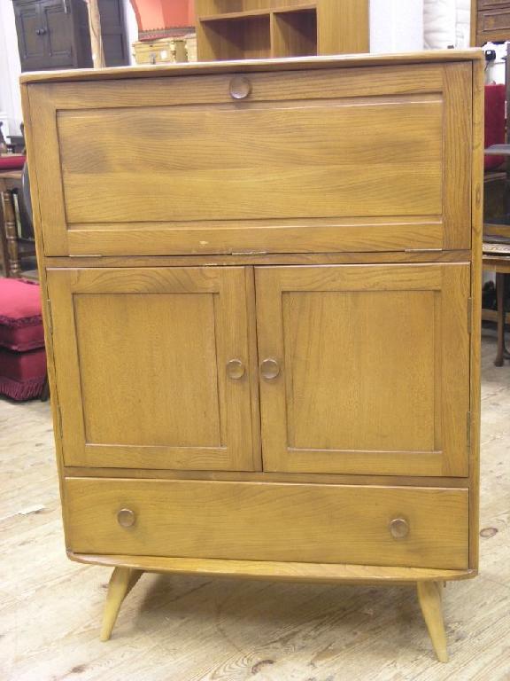 Appraisal: An Ercol light elm serving cabinet with panelled fall front