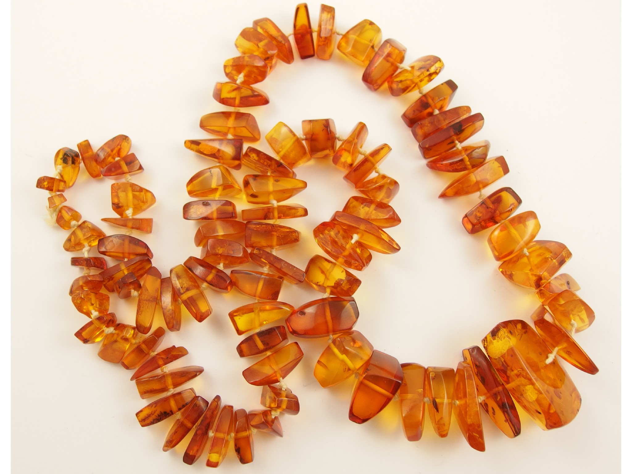 Appraisal: A long statement necklace of orange amber coloured beads